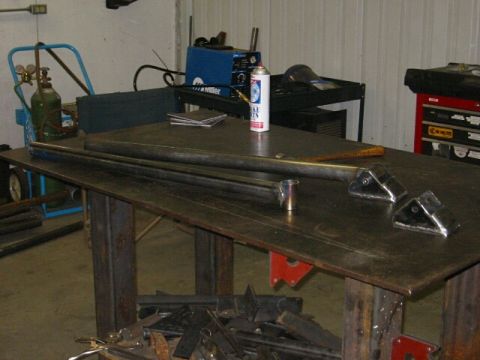 1994 Ford Bronco - Metal fabrication parts and welding equipment are laid out on a workbench in a garage or workshop.