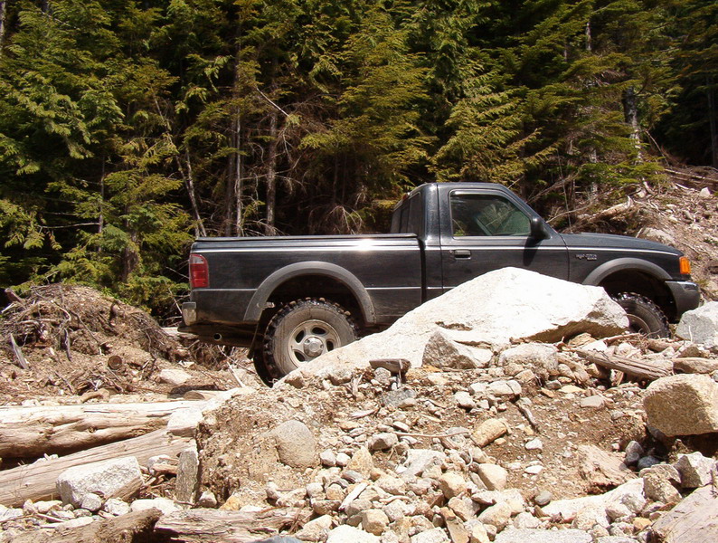 Dark pickup truck on a rocky forest trail.