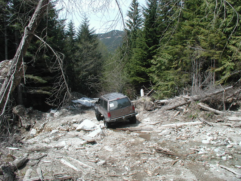 Brown SUV on a rocky, debris-filled mountain trail.