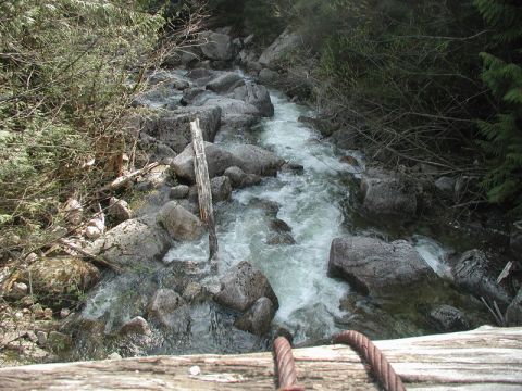 A stream flowing over rocks with wooden structure and cables in the foreground.