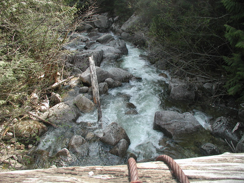 A stream flowing over rocks with wooden structure and cables in the foreground.