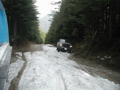 Black Ford pickup truck on a snowy forest road.