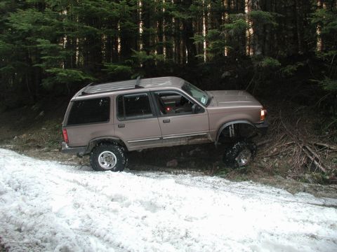 Lifted tan Ford Explorer on a snowy forest trail.