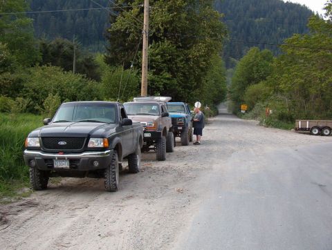 Several off-road trucks and SUVs parked on a gravel road.