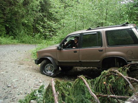 Tan SUV stuck in mud on a wooded trail.