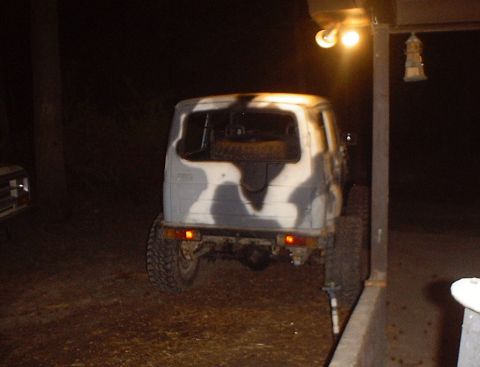 1989 Ford Bronco - A Suzuki Samurai with camouflage paint is parked outdoors at night, with a light illuminating the scene.