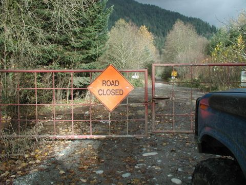 Blue Ford Bronco parked in front of a closed gate with a road closed sign.