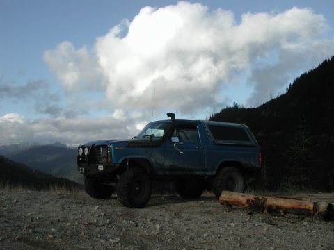 Blue lifted Ford Bronco with snorkel on a mountain overlook.