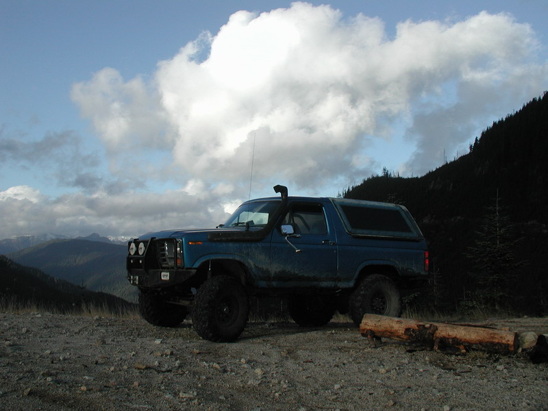 Blue lifted Ford Bronco with snorkel on a mountain overlook.
