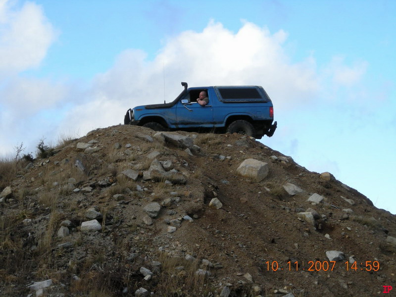 Blue Ford Bronco on a rocky hill with a snorkel and roof rack.
