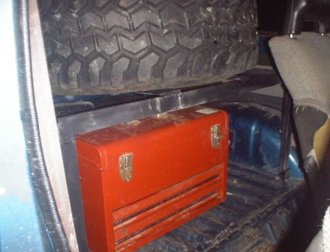 1989 Ford Bronco - A red toolbox sits below a spare tire in the rear of a vehicle.