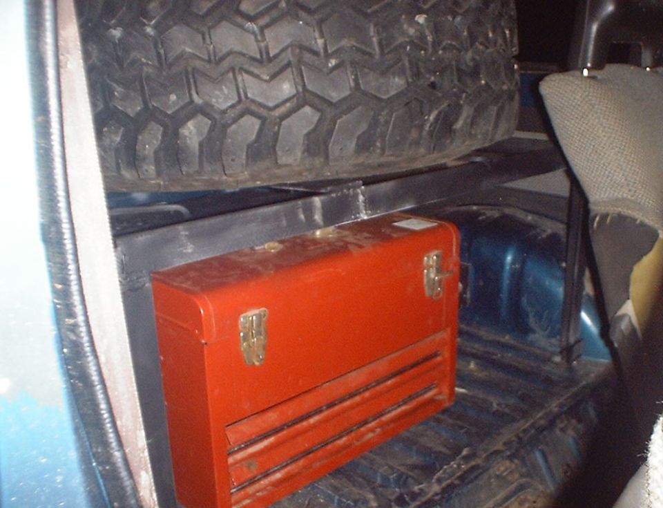 Spare tire and red toolbox in the cargo area of a vehicle