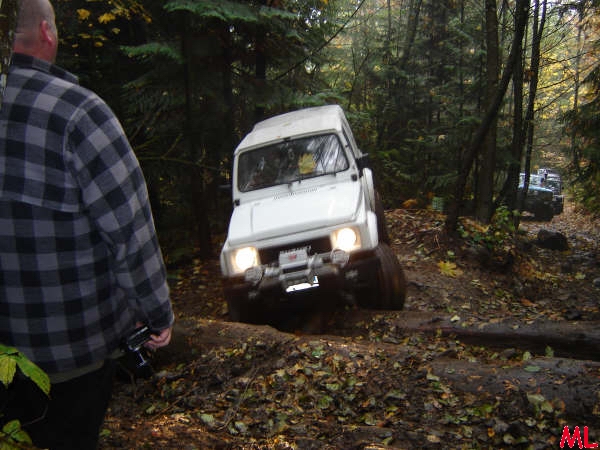 White off-road vehicle on a muddy trail in a forest.