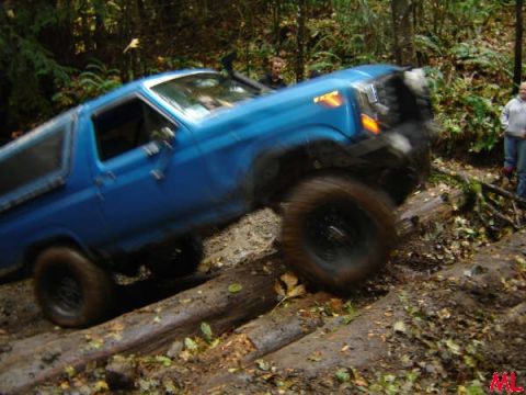 Blue Ford Bronco off-roading over logs