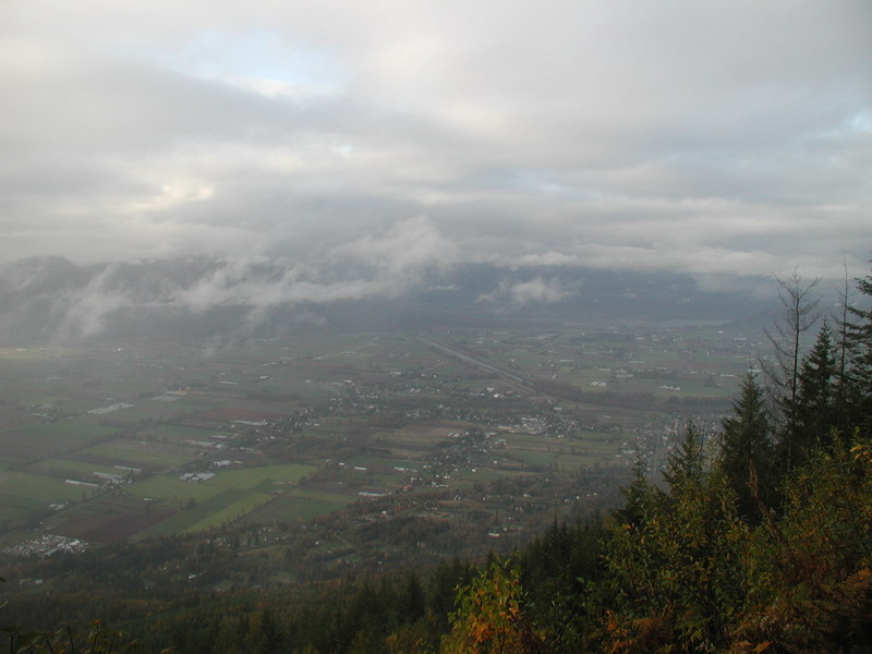 Valley with town and fields under a cloudy sky.