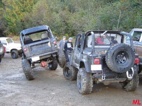 Two black Jeep Wranglers parked on a dirt path, one facing away from the camera.