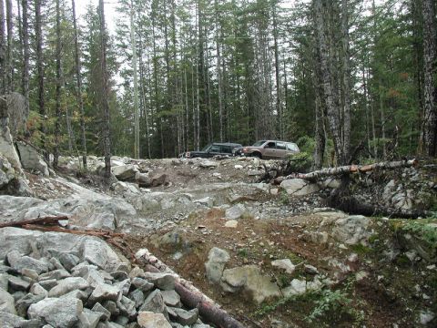 Two SUVs on a rocky, wooded trail.