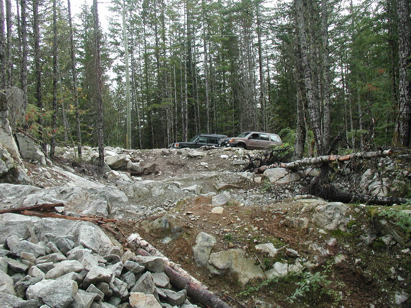 Two SUVs on a rocky, wooded trail.