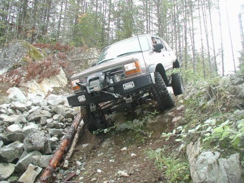 Brown SUV off-roading on a rocky, wooded trail.