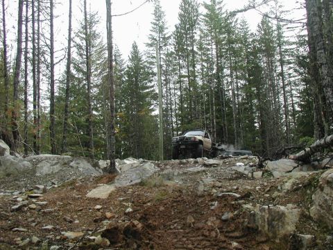 Two off-road vehicles on a rocky trail in a forest.