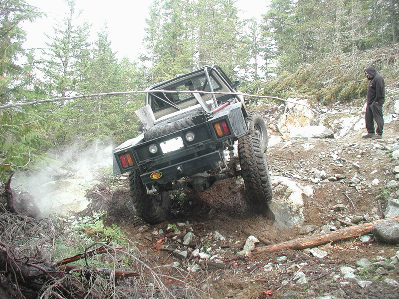 Off-road vehicle climbing a steep, rocky, and muddy hill.