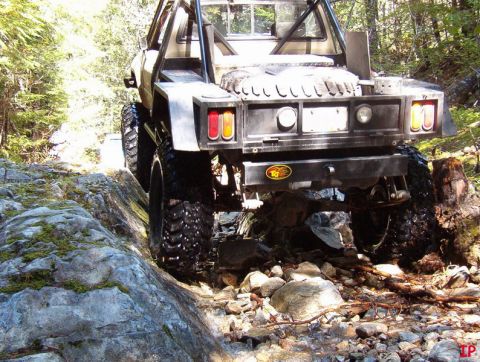 Rear view of a modified off-road pickup truck on a rocky trail.