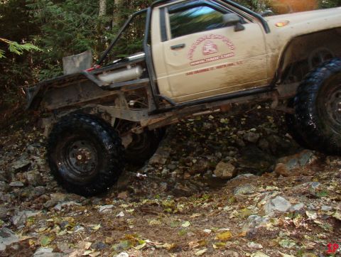 Tan off-road pickup truck with large tires on a rocky trail.