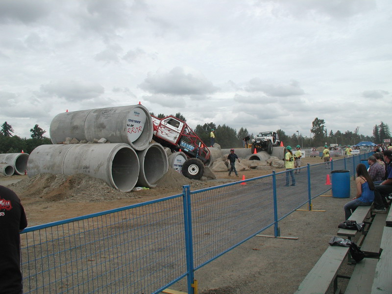 Modified truck on concrete pipes with flames, another SUV in background.