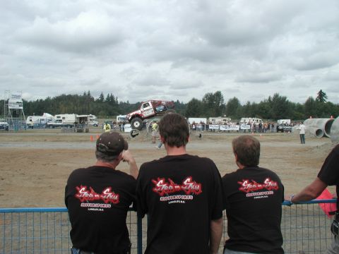 Monster truck jumping over a dirt mound with spectators watching.