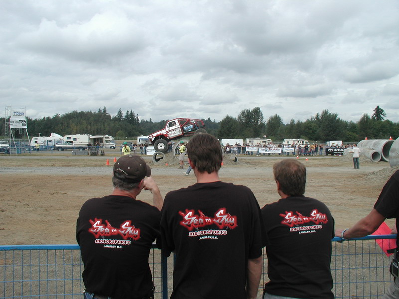 Monster truck jumping over a dirt mound with spectators watching.