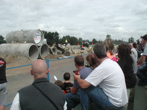 Off-road buggy driving through concrete pipes obstacle course with spectators.