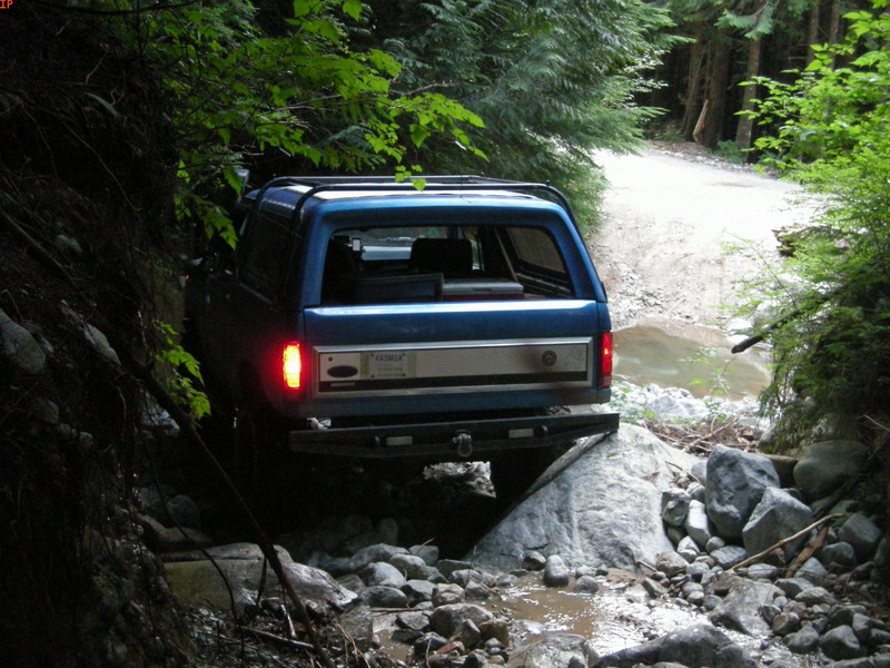 Blue Ford Bronco on a rocky trail with brake lights on.