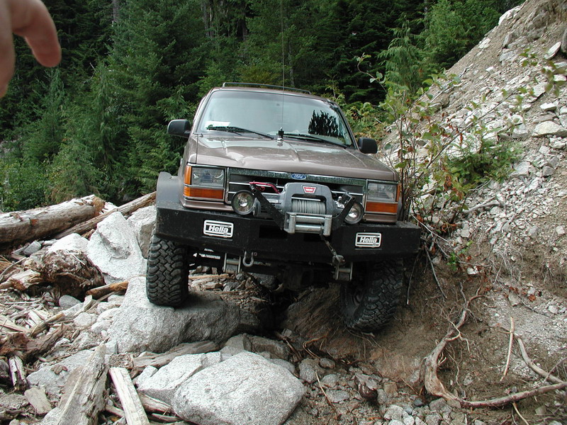 Brown Ford Explorer off-roading on a rocky trail with a winch.