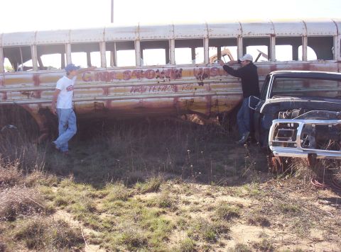 1988 Ford Bronco - An old, graffiti-covered school bus sits in a field next to a damaged truck.