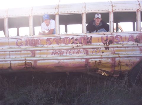 1988 Ford Bronco - A weathered school bus, possibly retired, shows graffiti and two individuals looking out from its windows.