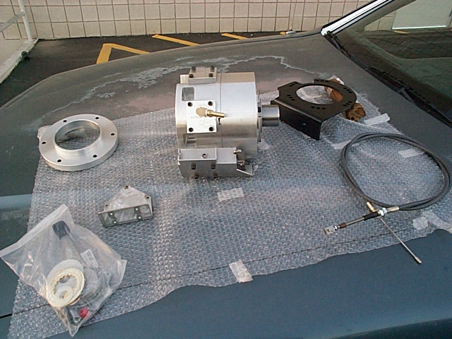 Aluminum housing, adapter ring, bracket, cable and hardware kit laid on bubble wrap