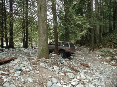 Brown SUV on a rocky forest trail.