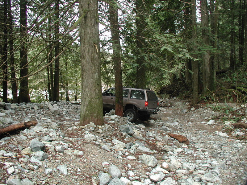 Brown SUV on a rocky forest trail.