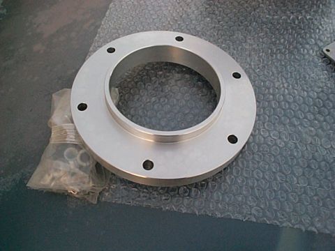 1994 Ford Bronco - A metal spacer with bolt holes is shown on a surface covered in bubble wrap, with a bag of fasteners nearby.
