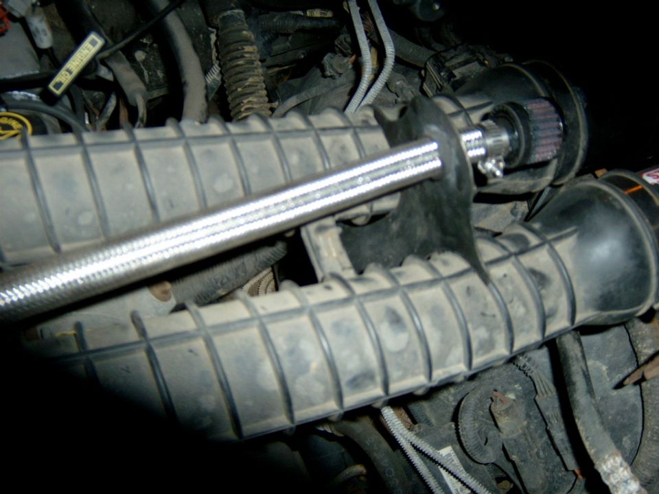 Ribbed black intake ducting and small red gauze breather filter in an engine bay