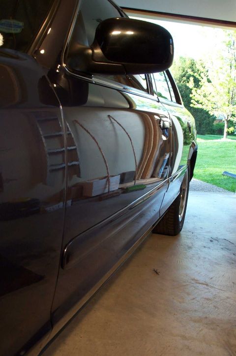 1998 Ford Crown Victoria - Reflections on the side of a dark sedan parked in a garage.