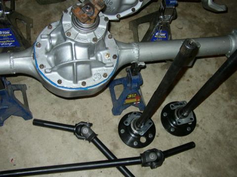 1995 Ford Bronco - Various automotive drivetrain components, including a rear axle and driveshafts, are laid out on the floor.