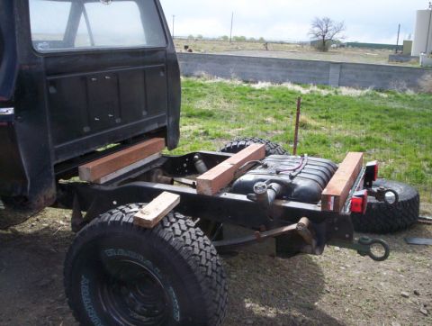 1978 Ford Bronco - The rear chassis of a truck is visible, a newly installed fuel tank supported by wooden blocks.