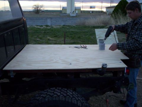 1978 Ford Bronco - A man works on modifying the bed of a truck with a new plywood floor.