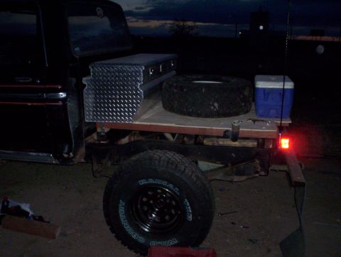 1978 Ford Bronco - Truck bed setup with a toolbox, spare tire, and cooler at dusk.