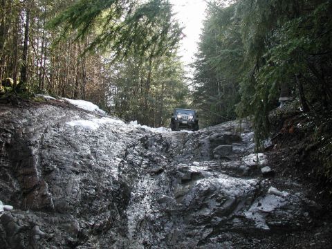 Jeep Wrangler on a rocky, snowy forest trail