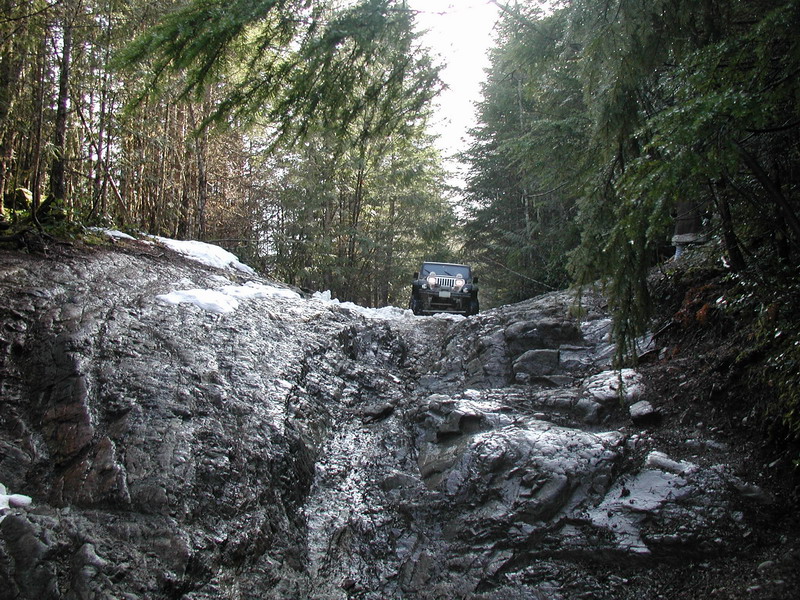 Jeep Wrangler on a rocky, snowy forest trail