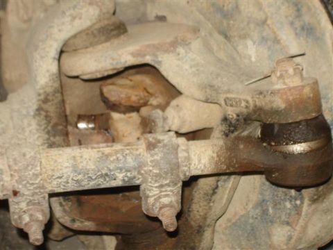 Close-up of rusty 1985 Ford Bronco suspension components, tie rod end, and steering linkage.