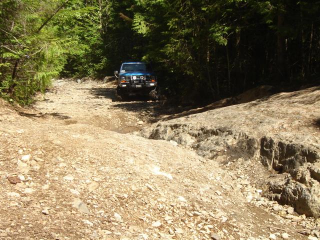 1985 Ford Bronco on a rocky, wooded trail.