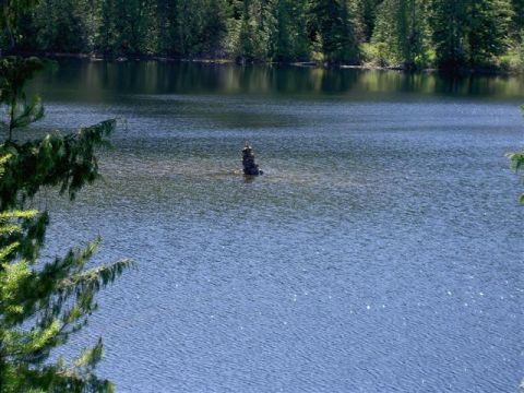 Lake with forest and a stone cairn.